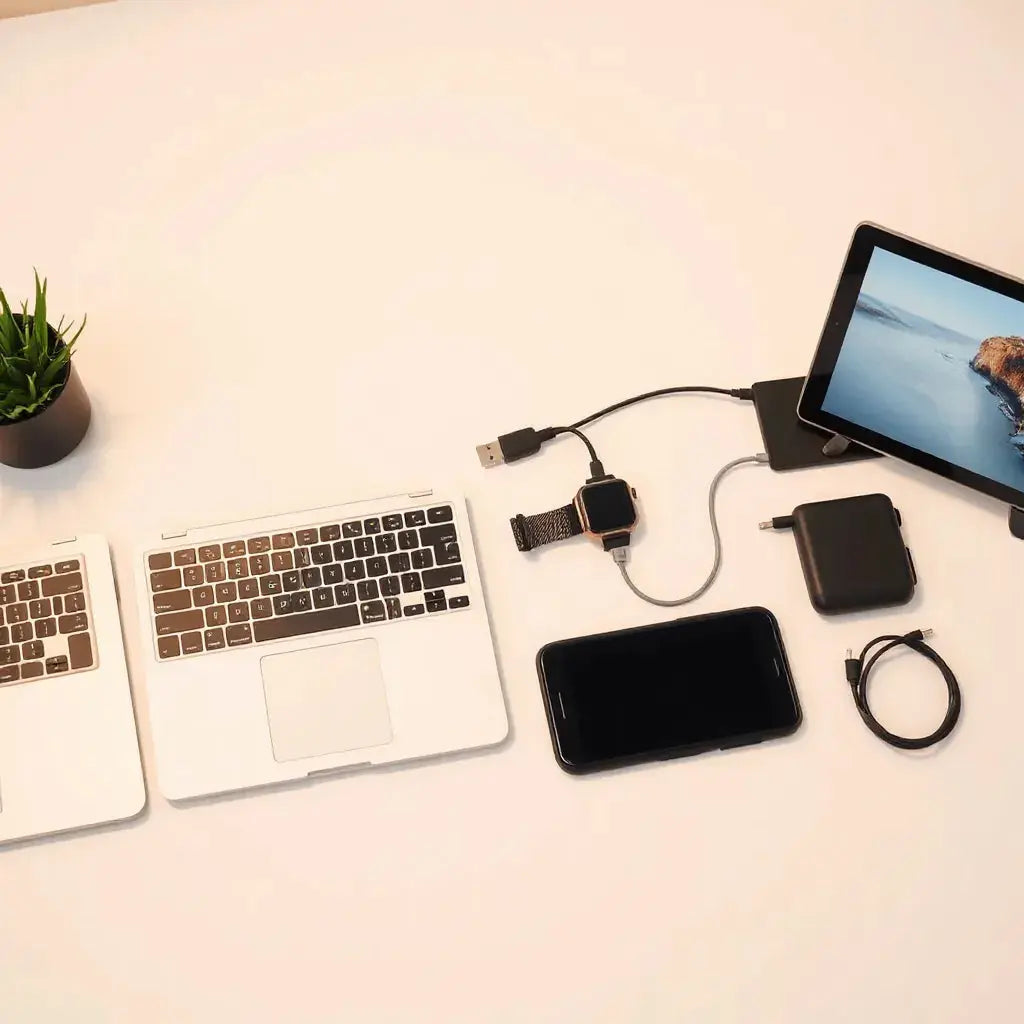 Minimal tech desk setup with laptop and phone plus premium charging cable, keyboard, and stand